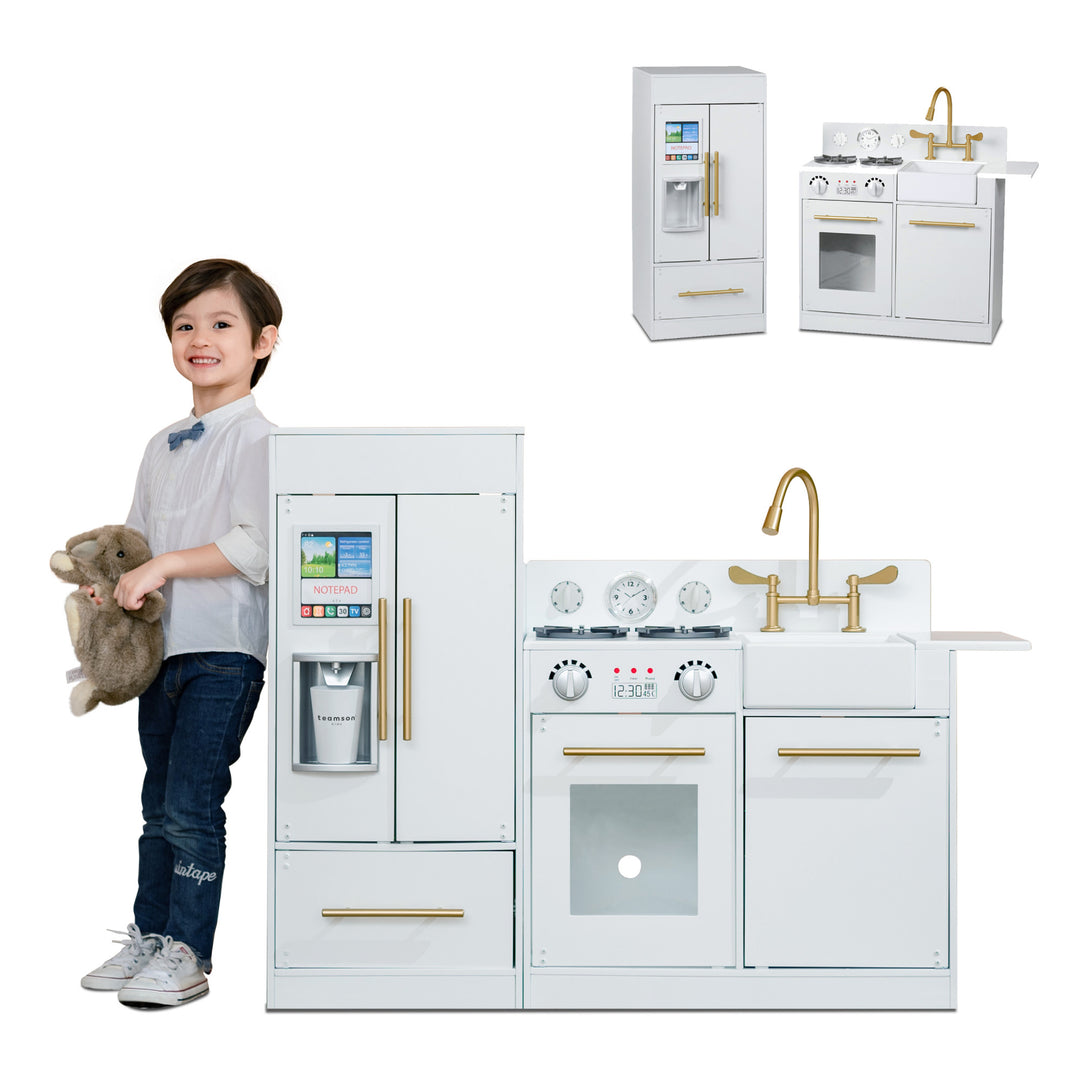 A child with a plush toy standing next to the Teamson Kids Little Chef Charlotte Modern Play Kitchen, White/Gold.