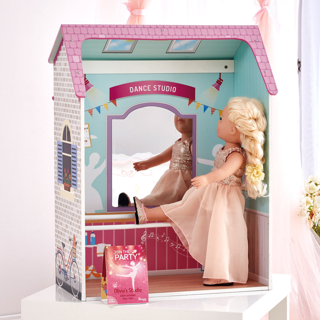 A 4-in-1 18" doll playset with the dance studio facade with a blonde doll dressed in a blush dress looking into the mirror.