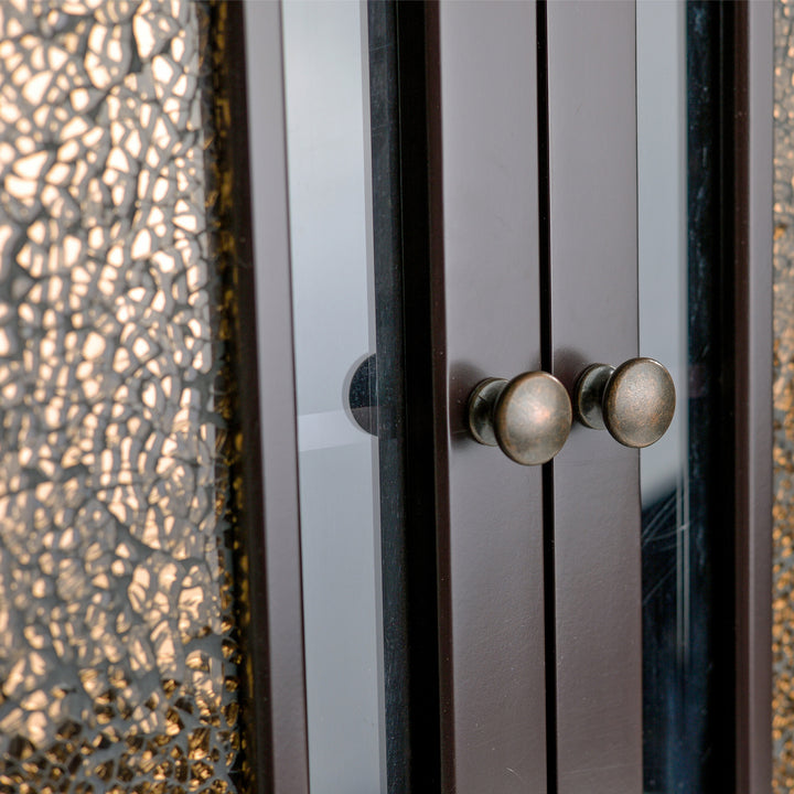 Close-up of rubbed bronze door pulls and glass mosaic inserts on a door