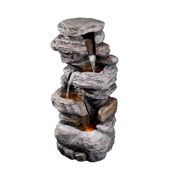 A Teamson Home Indoor/Outdoor 4-Tier Stacked Stone-Look Tall Waterfall Fountain with LED Lights made to resemble a stack of rocks with LED lights illuminating the water cascading down the tiers.