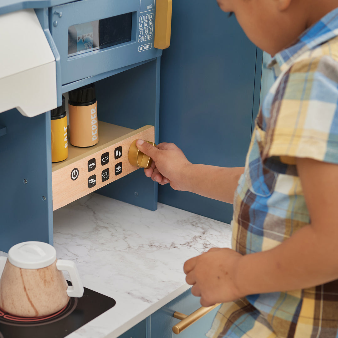 A child playing with a Teamson Kids - Little Chef Atlanta Large Modular Play Kitchen, Stone Blue/Gold.