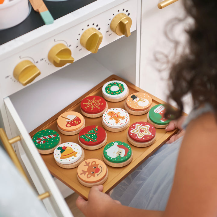 Child playing with a Teamson Kids - Little Chef Atlanta Large Modular Play Kitchen, White/Gold and festive pretend cookies.