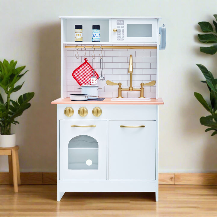 A white play kitchen with gold hardware and faux tile backsplash and plants