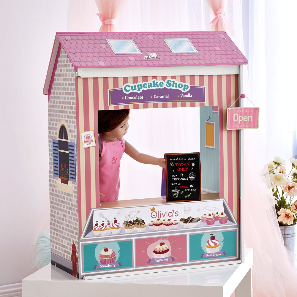 A 4-in-1 18" doll playset with the Cupcake Shop facade with an open sign, menu, and sandwich board and a doll with brunette hair.