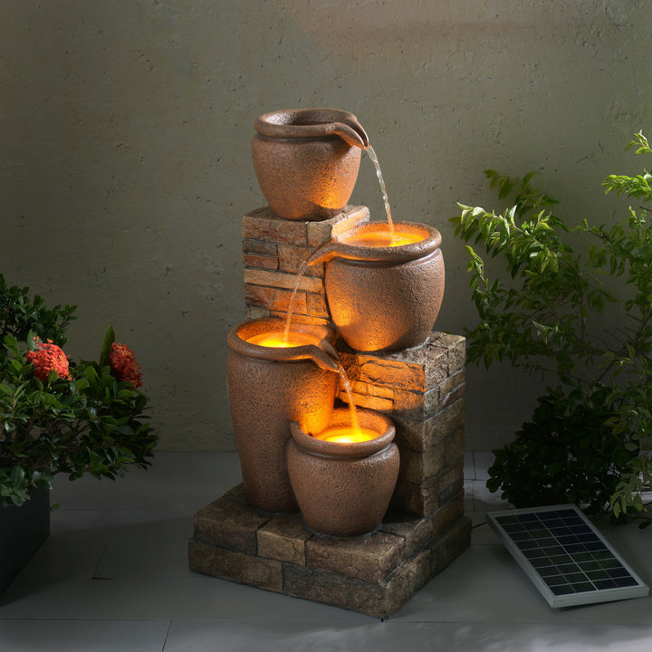 Teamson Home 30.71" 4-Tier Outdoor Solar Water Fountain with LED Lights, Terracotta in a garden setting at dusk.