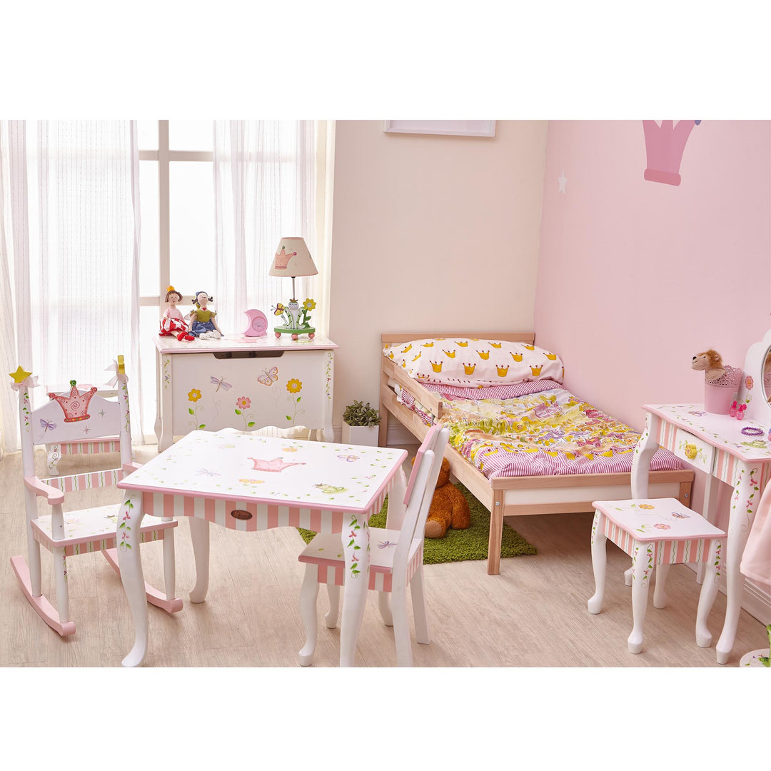 A girl's bedroom with a princess and frog theme with a storage chest, vanity, table and chairs set.