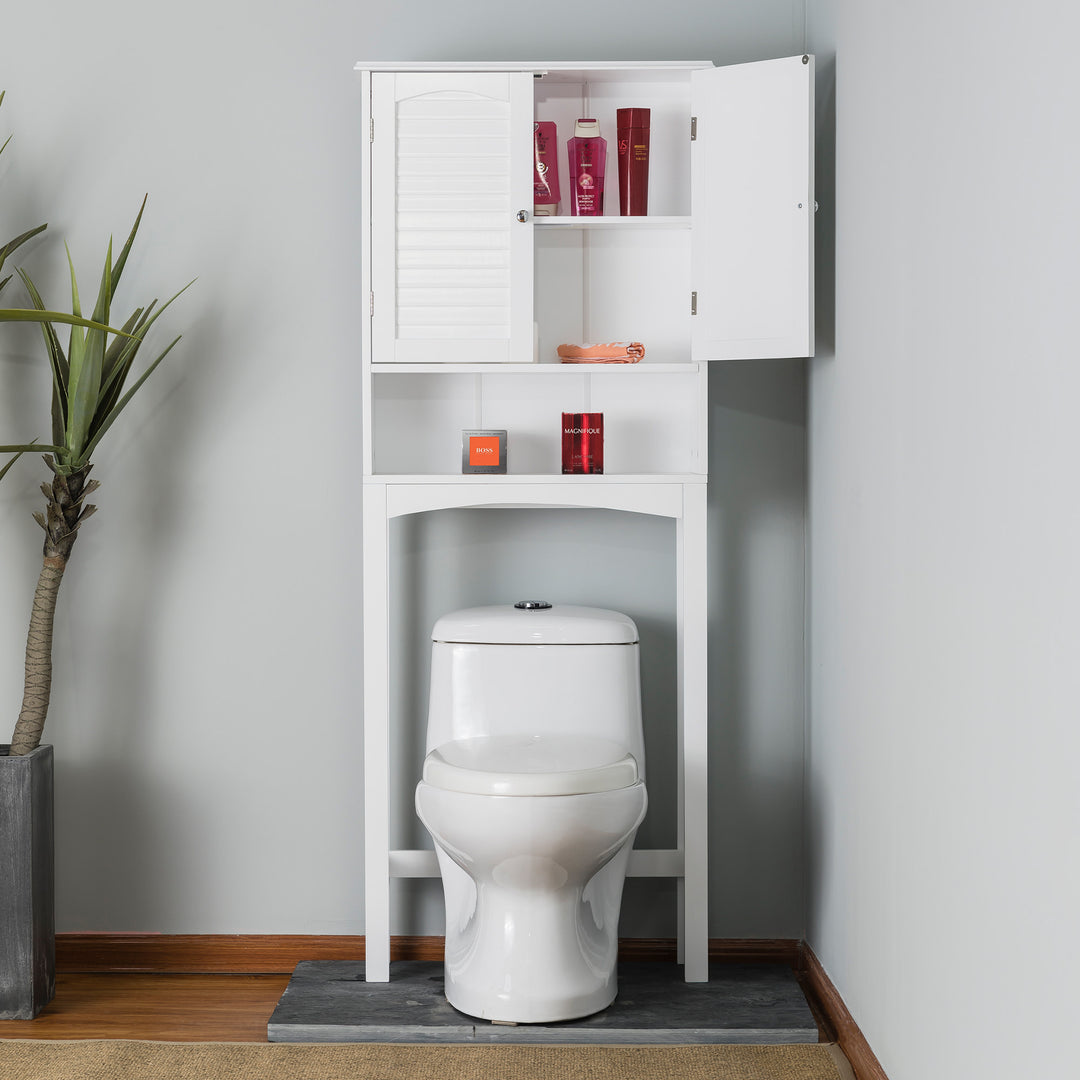 White Teamson Home Louis Over-the-Toilet Cabinet with Louvered Doors and an Open Shelf with a cabinet door open revealing toiletries in a corner of a gray bathroom