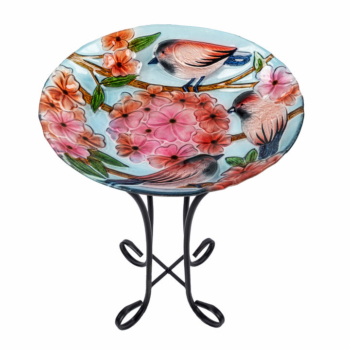 A 17.8" Robins & Blossoms Fusion Glass Birdbath with Metal Stand, Multicolored, with birds and flowers on a metal stand.