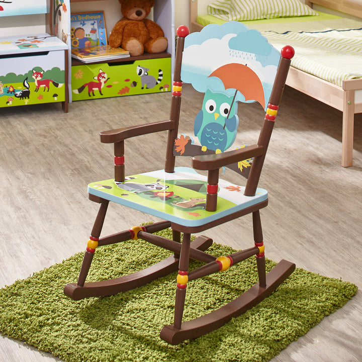 The multicolored Enchanted Woodland rocking chair on a green mat in the middle of a child's bedroom.