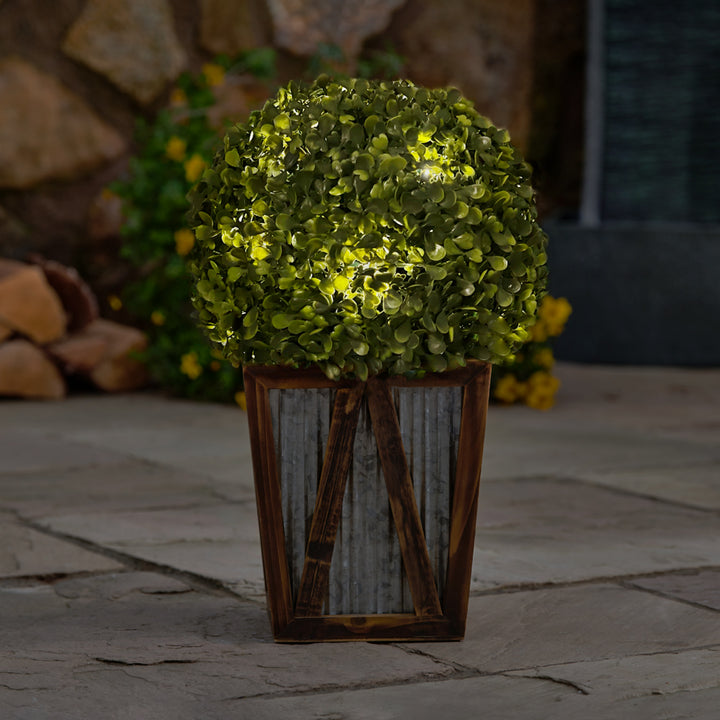 A Teamson Home Artificial Topiary Shrub with Solar LED Lights in Farmhouse Base plant in a decor pot.