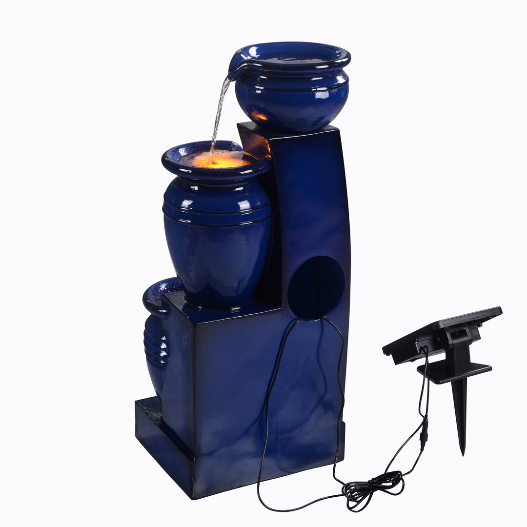 Teamson Home 28.74" Navy Blue 4-Tier Outdoor Solar Water Fountain with LED Lights on and a cord leading from the pump to the solar panel