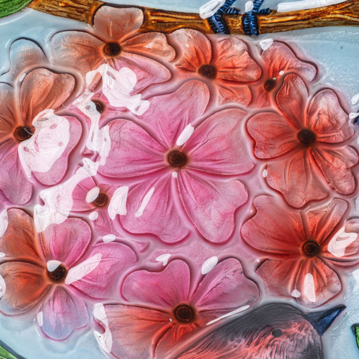 Close-up of the pink and orange flowers and birds on the fused glass bowl.