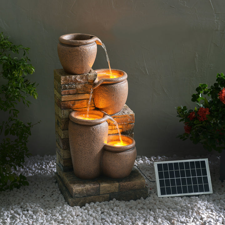 Teamson Home 30.71" 4-Tier Outdoor Solar Water Fountain with LED Lights, Terracotta with cascading urns at twilight.