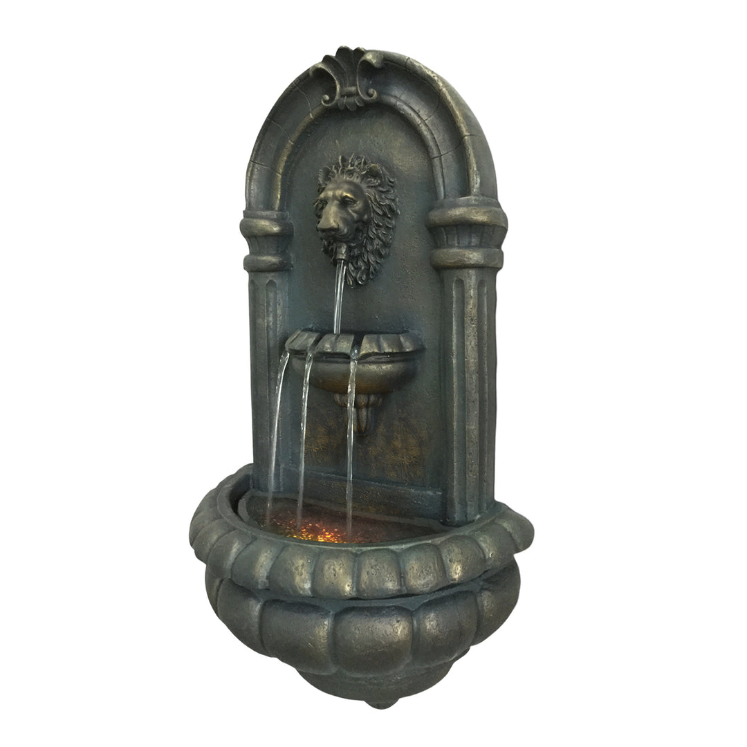 A view from the side of the Teamson Home Outdoor Tiered Lion Head Wall Water Fountain with water trickling out of the lion's head down to a middle tier and then to reservoir
