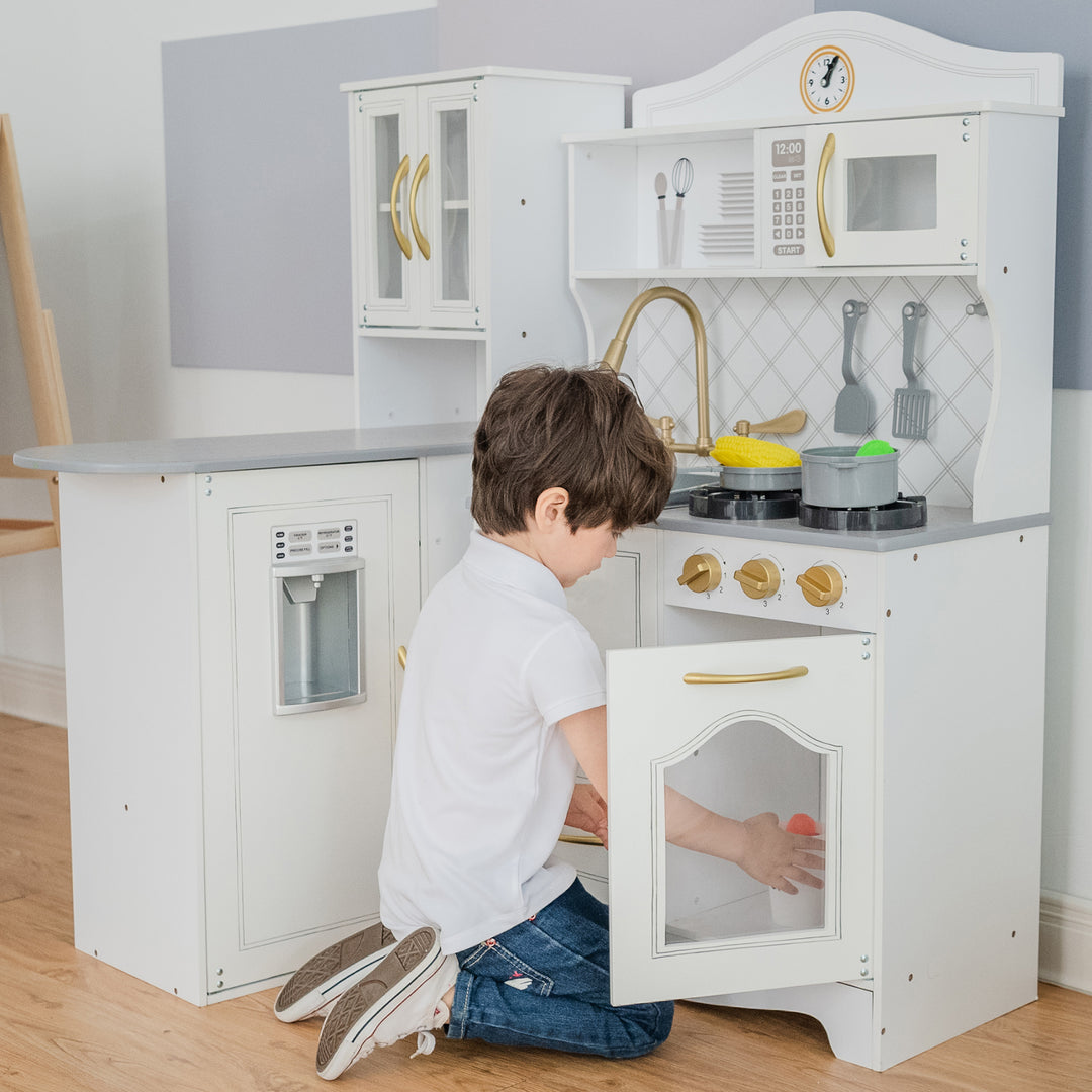 A little boy places something inside the oven underneath the stovetop.