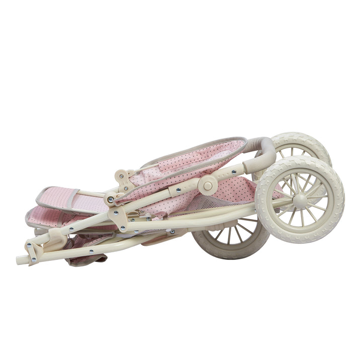 The tandem jogging stroller in its collapsed position, pink with gray polka dots and a white metal frame and tires.