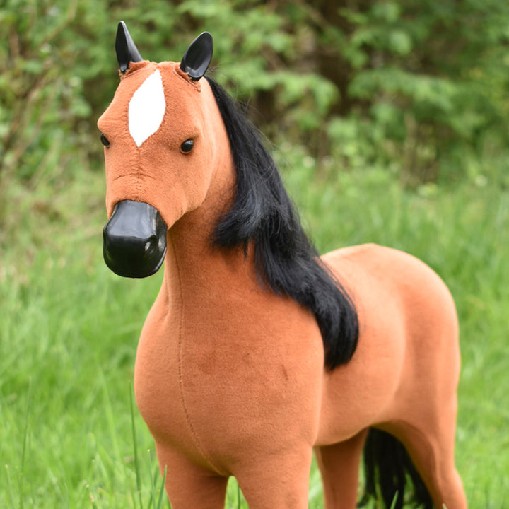 A brown and black horse for 18" Dolls standing in a grassy field.