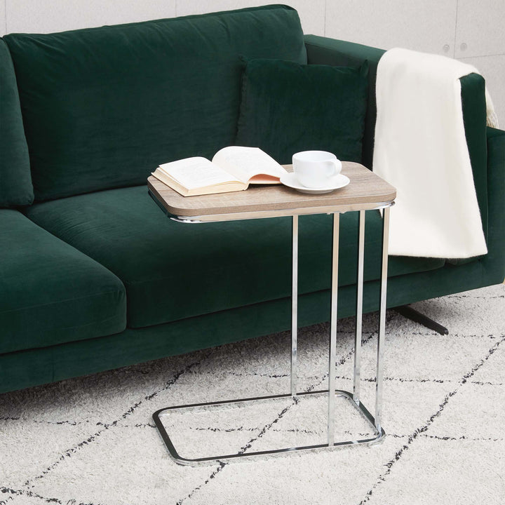 Teamson Home Cora C-shaped table with Salt Oak table top and metal base with a book and tea cup next to a green sofa