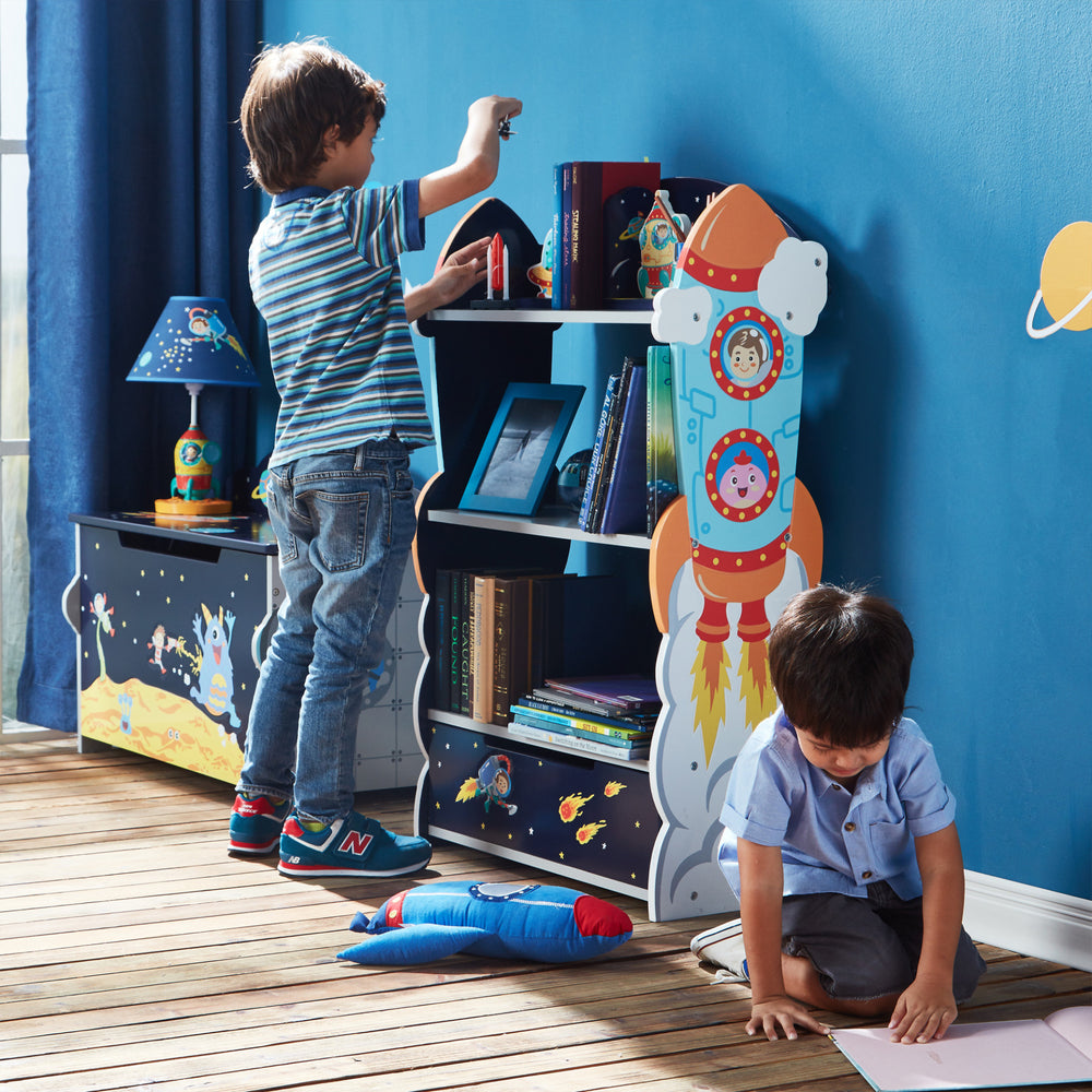 A blue wall in the room features the Fantasy Fields Kids Wooden Outer Space Bookshelf with Drawer, Blue as a storage solution.