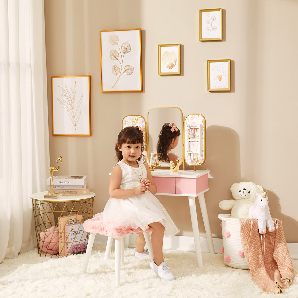 Fantasy Fields Little Lady Izabel Medium Floral Play Vanity Set with Matching Stool & Removable Faux Fur Cover, Floral Printed Panels, & Storage Drawer, White/Pink with a little girl sitting on the stool.