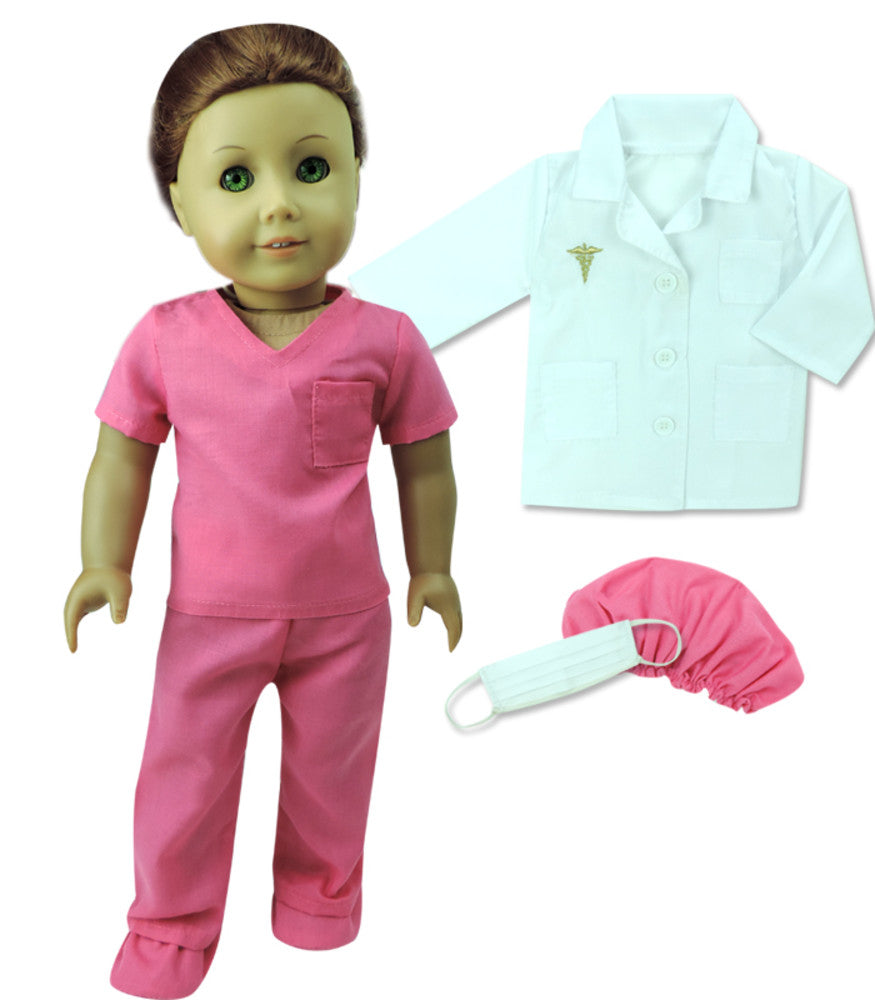 A doll dressed in pink surgical scrubs and shoe covers, a white lab coat, a pink scrubs cap, and a blue face  mask.