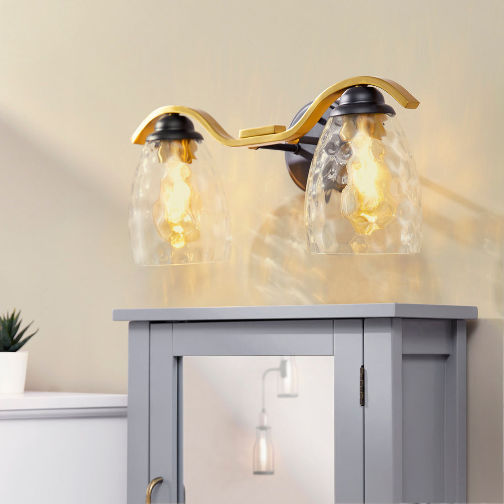 Teamson Home Heidi 2-Light Vanity Fixture with Clear Hammered Glass Cloche Shades, Black/Brass installed over a cabinet