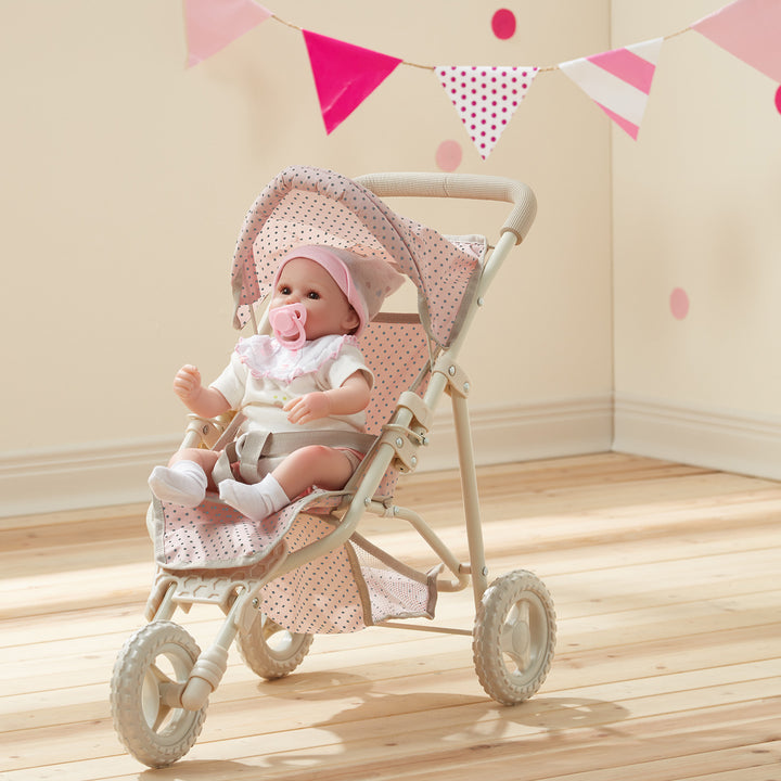 A baby doll sitting in the Pink with Gray polka dots Jogging Stroller, Pink.