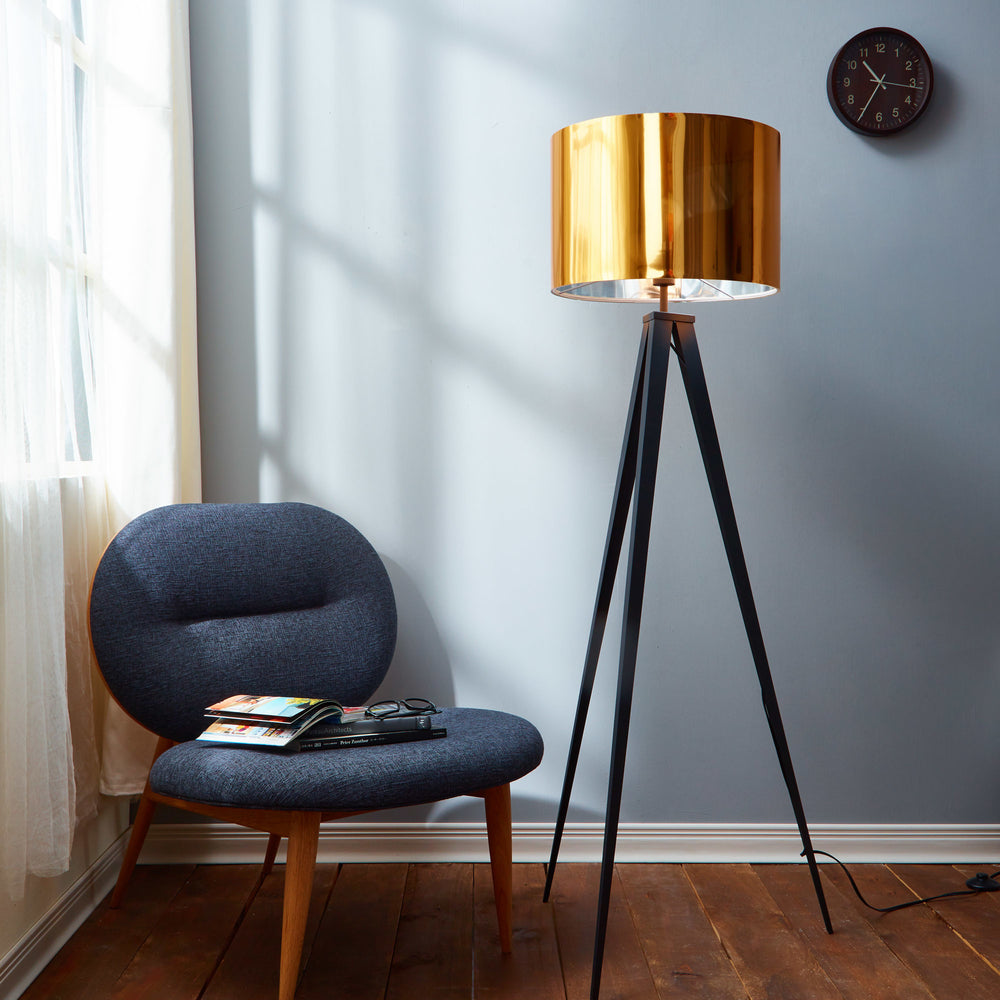 Teamson Home Romanza 60" Postmodern Black Tripod Floor Lamp with Gold Drum Shade next to a stylish chair and window
