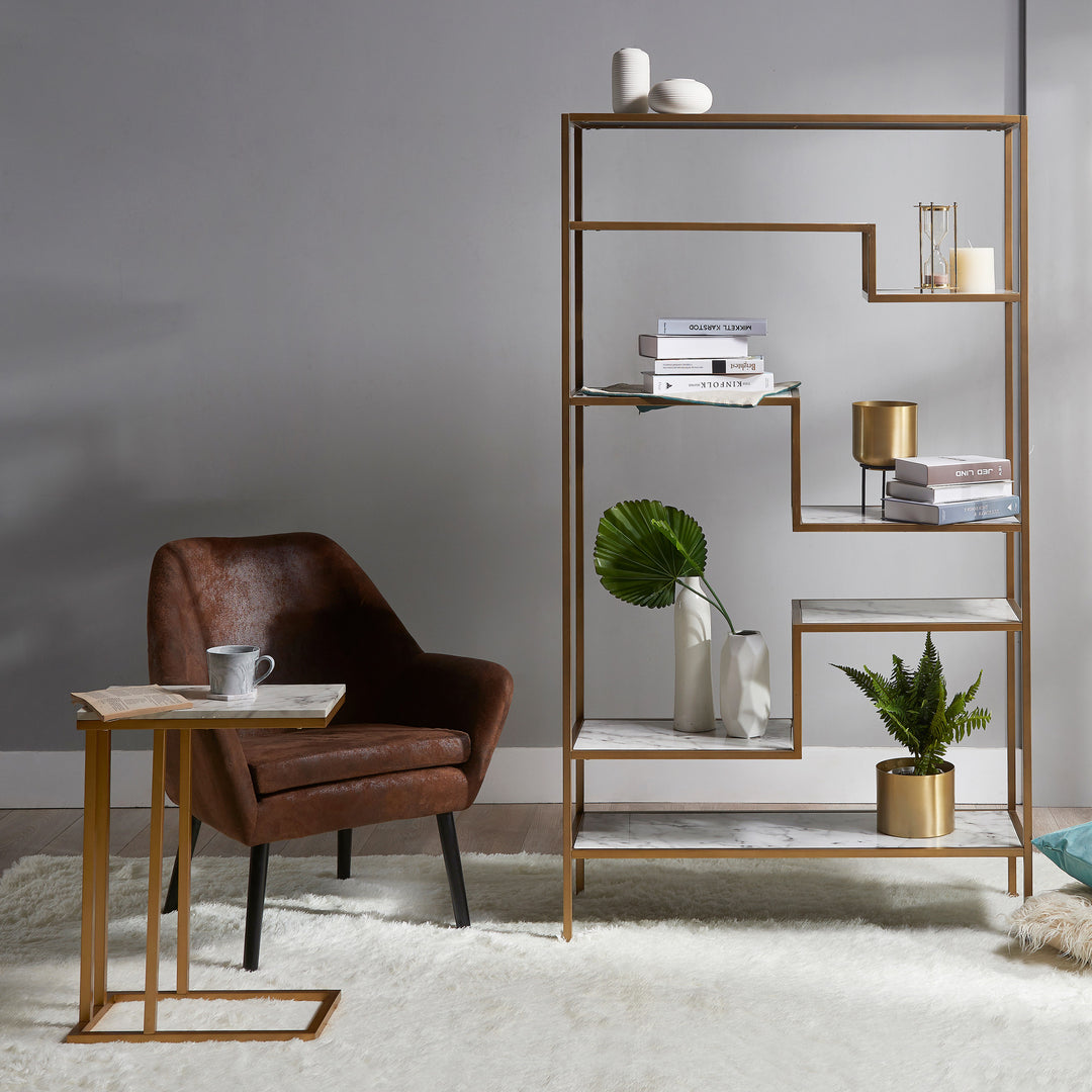 A Teamson Home Marmo Modern Marble 5-Tier Display Shelf with a faux marble top in a room with a chair and a plant.