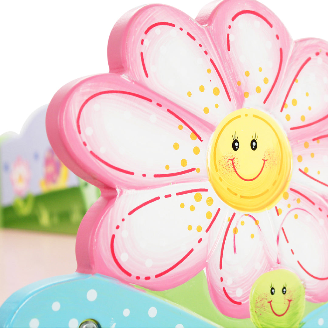 Closeup of the detailed flowers on the bookshelf, with pink and white petals and a yellow center with a smiley face.