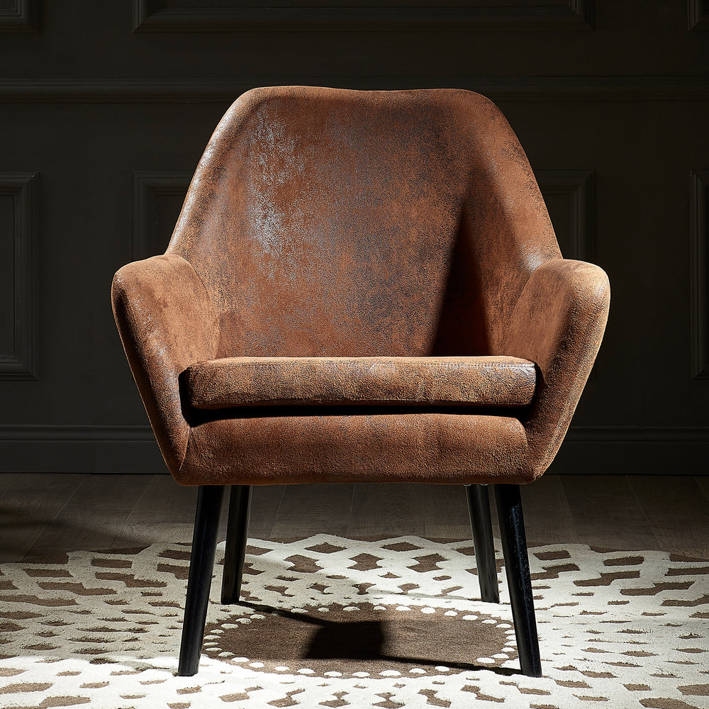 A stylish Teamson Home Divano Armchair with Aged Fabric and Solid Wood Legs, Brown on a rug in a dark room.