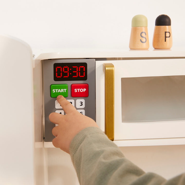 Child pushing the start button on the play microwave on the Teamson Munich Play Kitchen. 