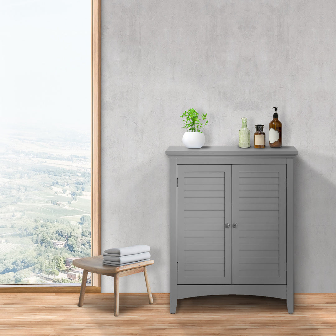 A minimalist room with a Gray Teamson Home Glancy Floor Cabinet with two louvered doors with decor on top next to a large window against a gray wall