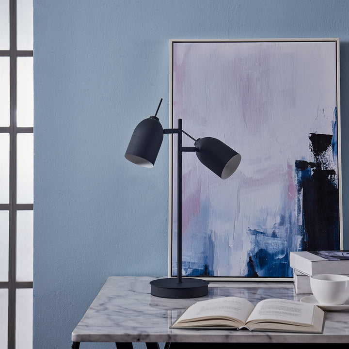 Teamson Home's Mason Modern Adjustable Double Light Table Lamp, Black with a book on it and a painting on the wall.