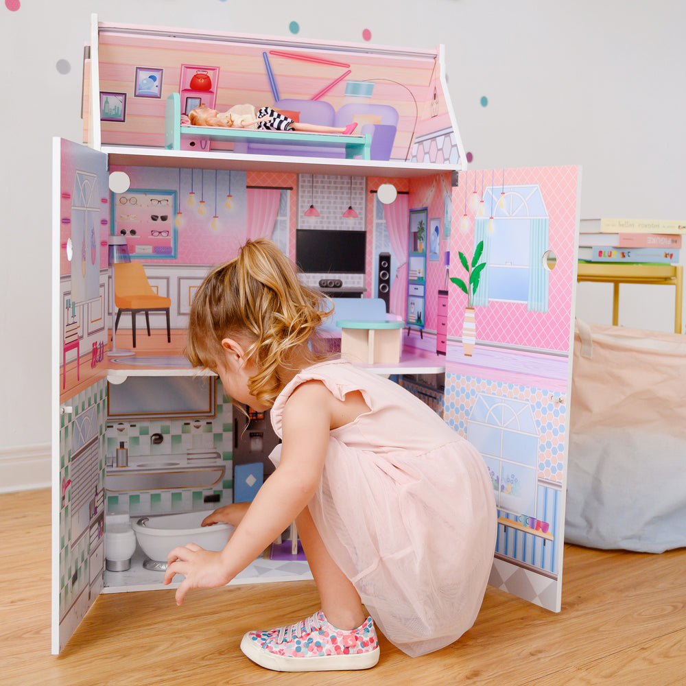 A little girl playing with Olivia's Little World Dreamland Glass-Look Dollhouse and accessories.