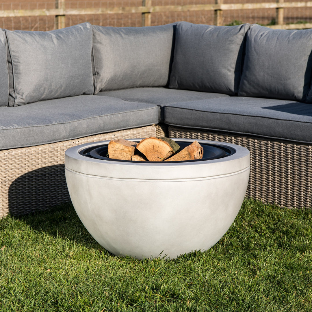 Teamson Home 30" Wood Burning Fire Pit with Faux Concrete Base in Gray next to an outdoor seating area