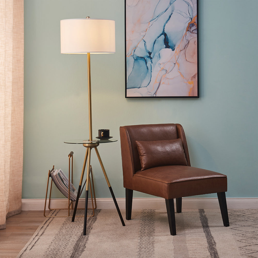 A living room with a comfortable Teamson Home Marc Faux Leather Lounge Chair with Pillow and Solid Wood Legs, Brown and a gold floor lamp.