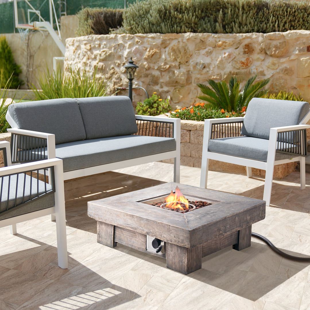 Outdoor patio with a Teamson Home 35" Square Retro Wood Look Gas Fire Pit table, sofa, and two chairs.