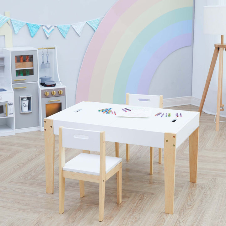 A white and wood child-sized table and two chairs in a playroom with crayons and paper on the tabletop.
