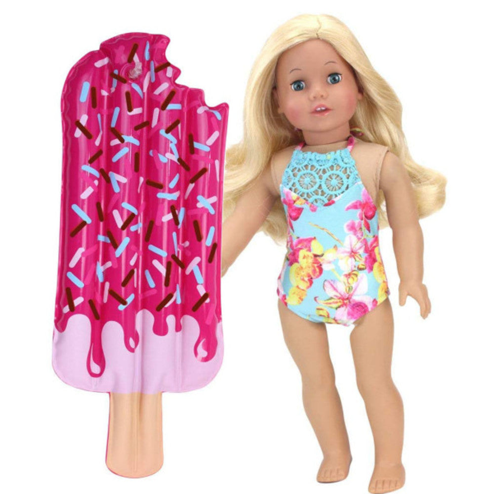 A popsicle-shaped inflatable raft next to a blonde doll with blue eyes in a blue floral and lace swimsuit.