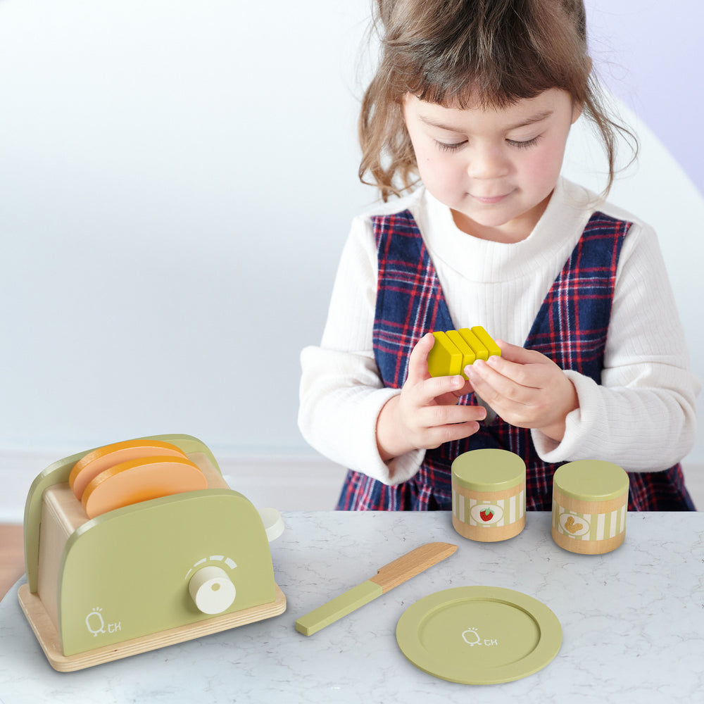 A girl playing with the Teamson Kids Little Chef Frankfurt Wooden Toaster Play Kitchen Accessories, Green in her play kitchen.