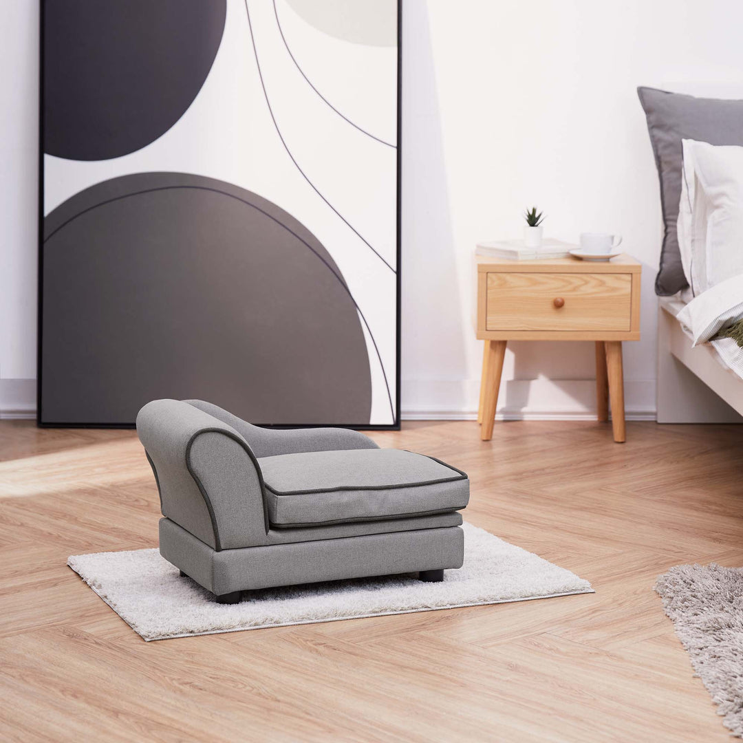 A gray chaise lounge pet bed on a small rug in a bedroom.