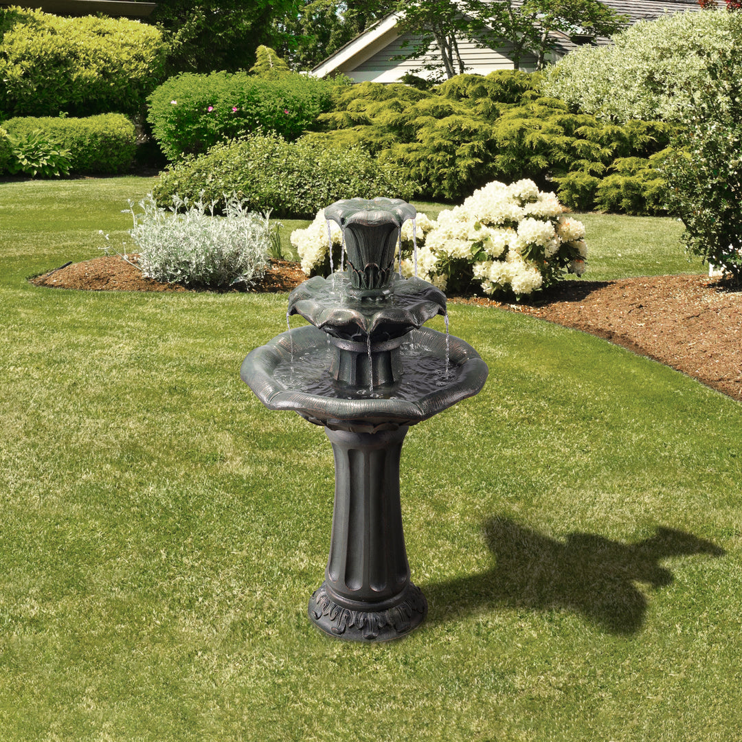 Teamson Home Outdoor Lily Flower Stone 3-Tier Waterfall Fountain, Gray in a well-manicured garden lawn, adding a sense of natural tranquility.
