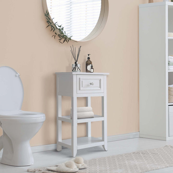 The Teamson Home Dawson Accent Table with storage drawer and shelves, White, below a mirror and next to a toilet