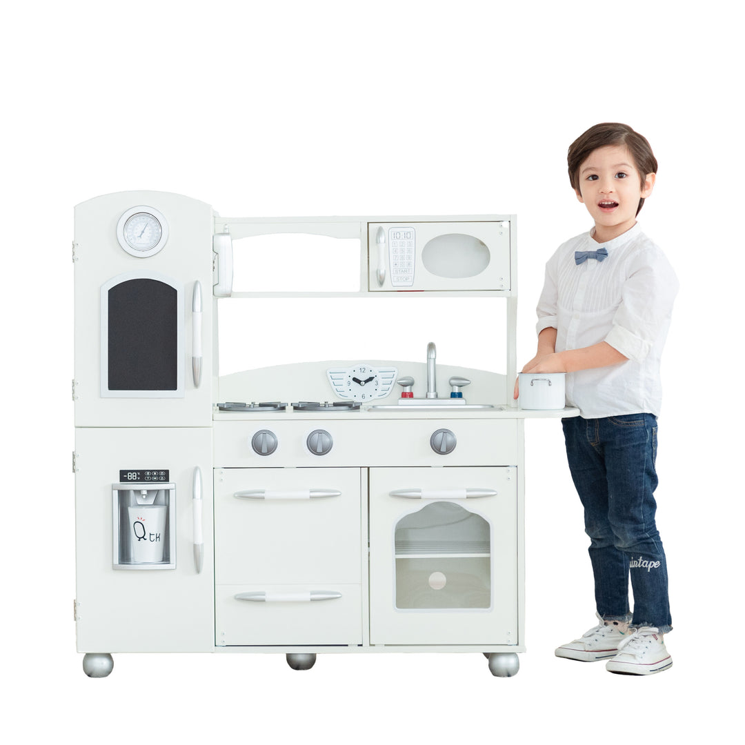 A child standing next to a Teamson Kids Little Chef Westchester Retro Kids Kitchen Playset, Ivory with interactive features.