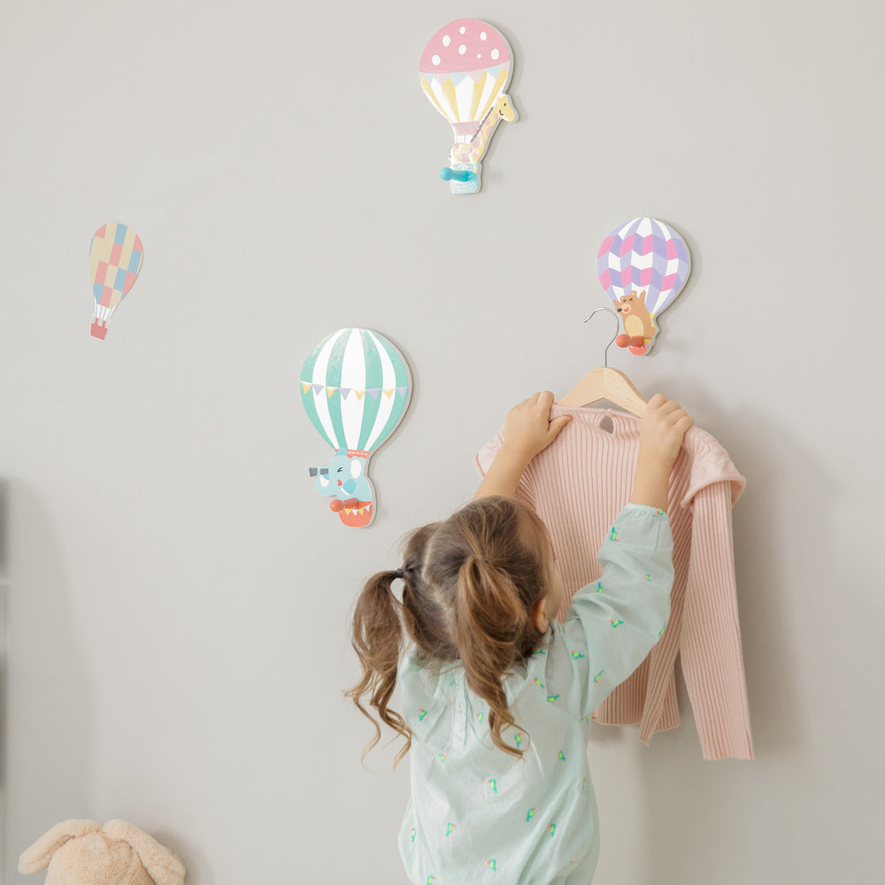 A girl holding a Fantasy Fields Kids Peg Coat Hanger Hooks on a swinger.