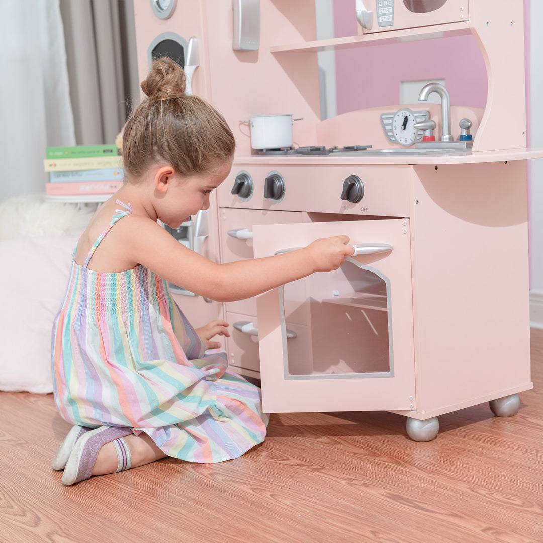 A young girl playing with a Teamson Kids Little Chef Westchester Retro Play Kitchen, Pink.