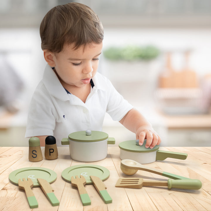 Toddler playing with Teamson Kids Little Chef Frankfurt Wooden Cookware Play Kitchen Accessories, Green on a wooden table.