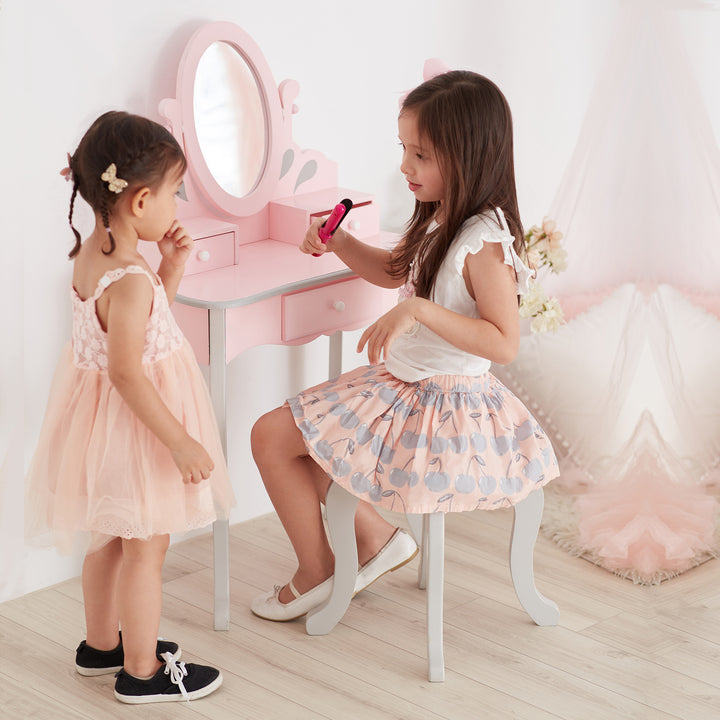 Two little girls sitting in front of a Teamson Kids Little Princess Rapunzel Vanity Playset in pink.