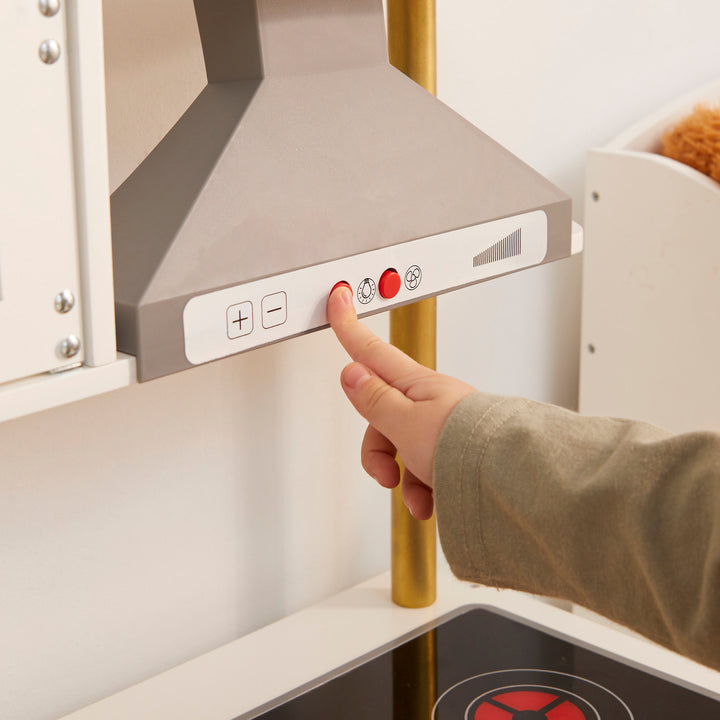 Child pushing the button of the oven hood range on the Teamson Munich play kitchen.